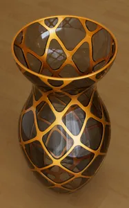 Glass vase with metal frame spiralling in both directions and a metal lip