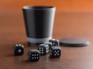Two-tone playing dice and a cup with a lid.