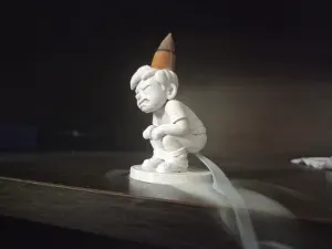 Backflow incense burner – a squatting boy pooping